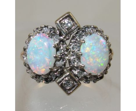 A vintage opal and diamond ring set in yellow and white metal, the two opals with nice red, green blue colour play are claw s