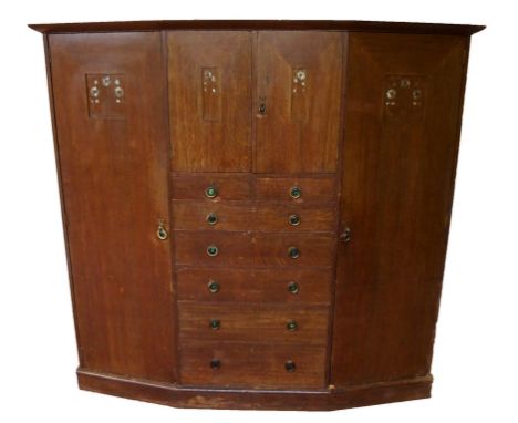 A Scottish Arts and Crafts oak wardrobe with a pair of central doors above seven graduated drawers flanked by a pair of doors