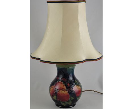 A large Moorcroft pomegranate pottery lamp base, the tubed body on a mottled blue green ground, with original shade