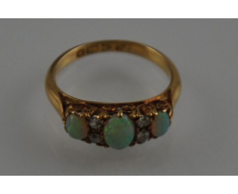 An opal and diamond seven stone ring, Victorian scroll set in an 18 carat yellow gold band ring