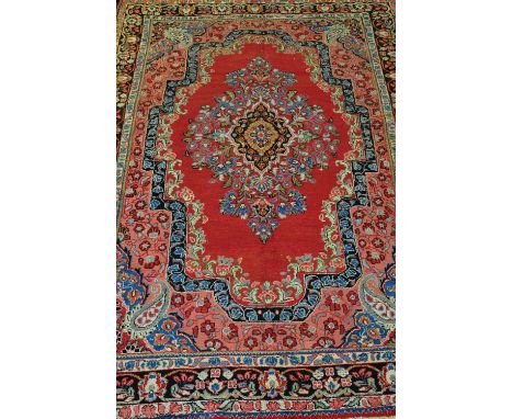 A Persian Sargh brick red ground carpet woven with a central floral medallion within a wide multi border, 300 x 200cm