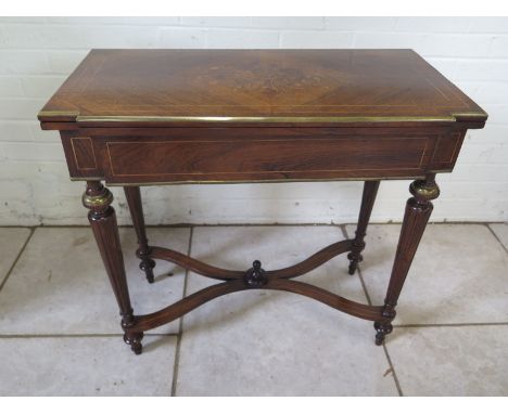 A 19th Century marquetry inlaid rosewood foldover card table with brass mounts on turned fluted legs united by a shaped stret