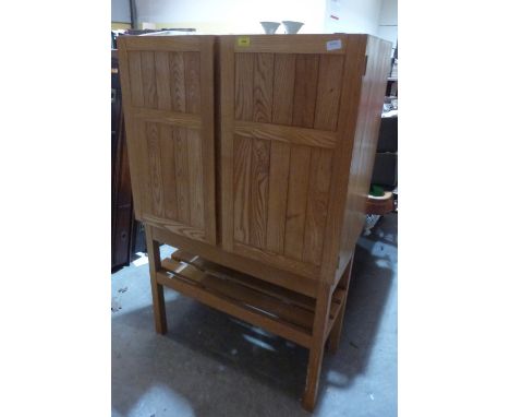 Reynolds of Ludlow. An ash cabinet enclosed by a pair of doors over a slatted shelf. 36' wide