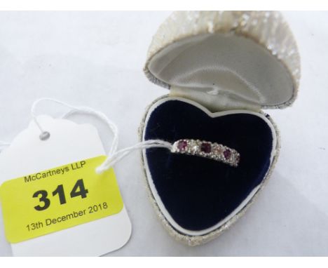 A seven stone ruby and diamond ring. In white gold marked 18. 2.8g gross. Size R