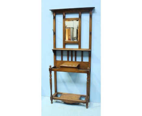 An early 20th century oak hall stand, with plain cornice, above a central rectangular bevelled mirror and six iron hooks, ove