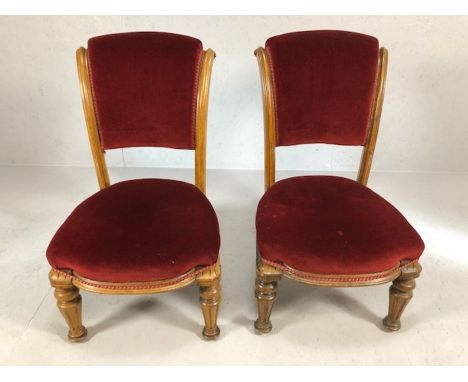 Pair of carved light wood low bedroom chairs with red velvet seats and backs