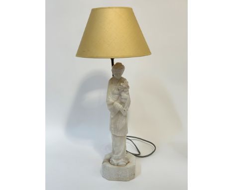 A carved Soapstone Chinese standing figure lamp in the form of a lady carrying flowers on an octagonal base (height including