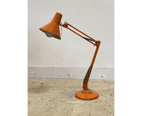 A vintage anglepoise lamp with orange finish, conical shade and stepped circular base