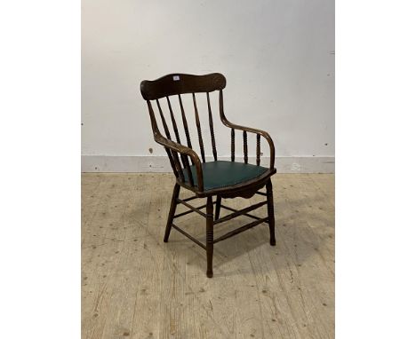 An early 20th century oak desk chair, bobbin turned spindle back over upholstered seat, raised on ring turned supports, H91cm