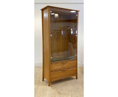 Ercol, a late 20th century blonde elm bookcase display cabinet, two glazed doors enclosing an illuminated interior with three