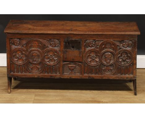 A 17th century and later oak six-plank chest, hinged rectangular top with notched ends above a panel carved with medieval tra