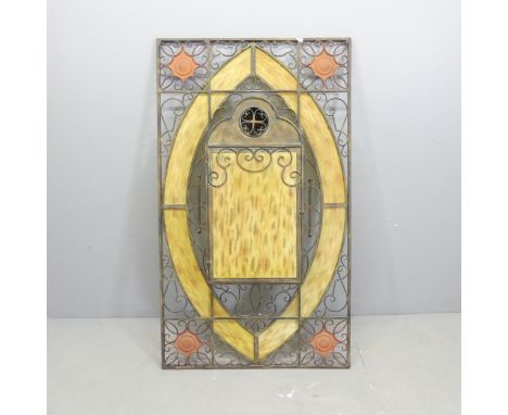 A large wrought-iron and yellow stained glass candle stand wall panel, with allover pierced scrolled decoration and central c
