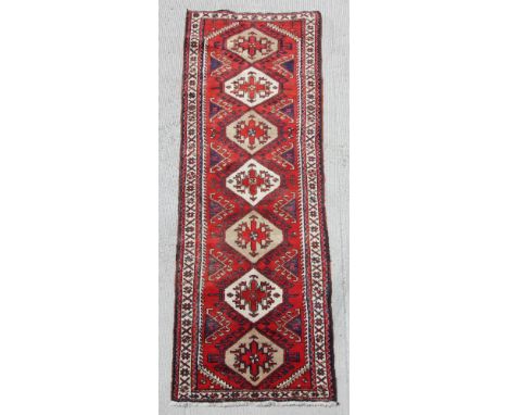 A Persian hand knotted runner with stylised geometric design, on a beige ground, 290 by 90cms (388).