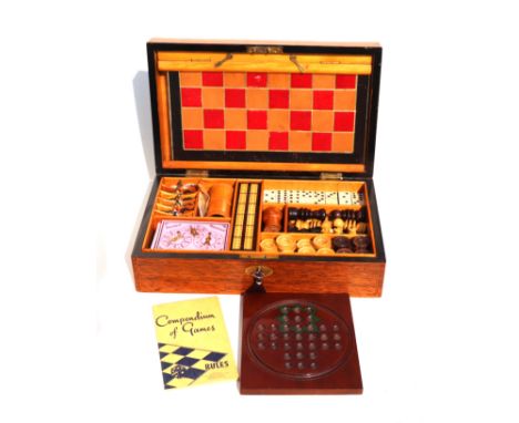 An early 20th century mahogany games compendium fully fitted with dominoes, chess, draughts, cribbage and other games, with a