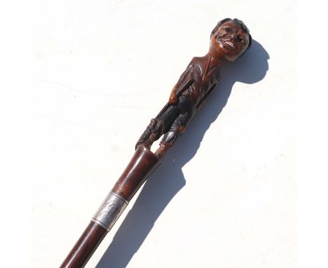 A 19th century mahogany walking stick with figural handle depicting a young boy wearing ragged clothes holding a broom, with 