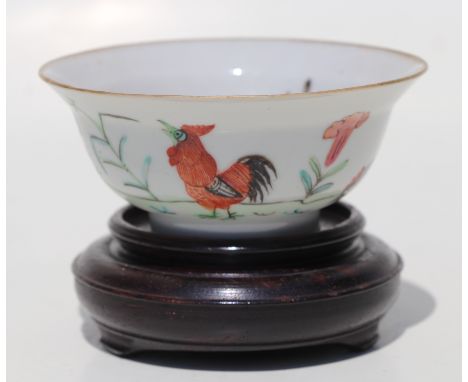 A Chinese famille rose bowl decorated with chickens, on a hardwood stand, red seal mark to the underside, 9.5cms diameter.