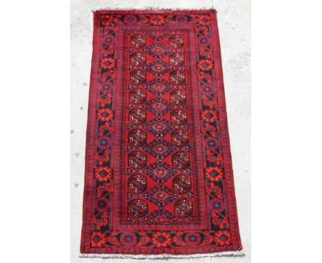 A Persian Turkoman hand knotted runner with repeat geometric design, on a red ground, 230 by 117cms (11).