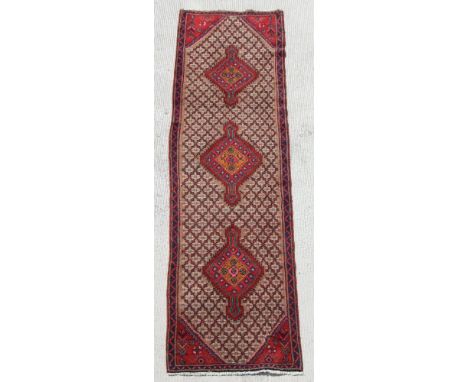 A Persian hand knotted runner with repeat design within a geometric border, on a beige ground, 290 by 80cms (SH6).