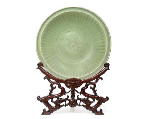 A Longquan Celadon Dish, Ming dynasty, carved with a central foliate panel within a broad fluted border, 41cm diameter, with 