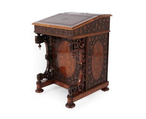 A Victorian Burr Walnut and Carved Davenport, circa 1870, with gilded leather writing surface and hinged lid enclosing a mapl