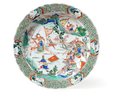 A Chinese Porcelain Dish, Kangxi, painted in famille verte enamels with a battle scene within a brocade border 37.5cm diamete