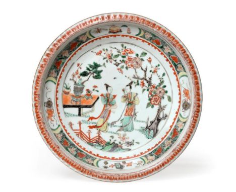 A Chinese Porcelain Charger, Kangxi, painted in famille verte enamels with figures in a fenced garden within a foliate border