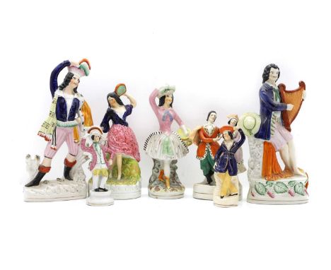 A collection of seven Staffordshire pottery figures, mid-19th century, modelled as dancers and a man playing the harp, 32cm t
