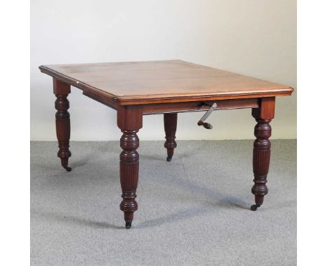 A Victorian walnut wind out extending dining table, with an additional leaf, on turned and reeded legs, with winder150 x 105 