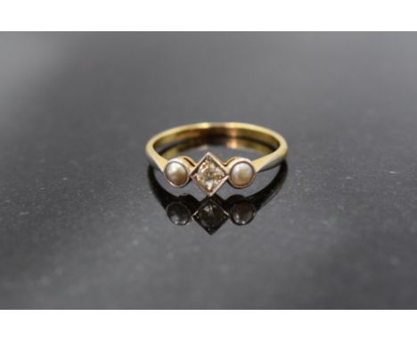 An 18ct gold platinum set diamond and pearl ring, the central brilliant cut stone within a beaded square setting, flanked by 