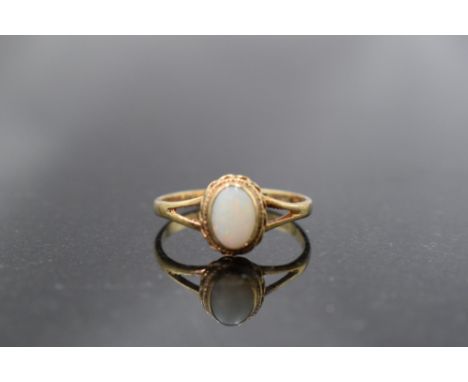 An opal solitaire ring of matt finish in a decorative collared mount to open shoulders on a 9ct gold loop, size O &amp; appro