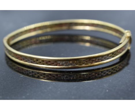 A modern 9ct gold triple coloured hinged bangle having brick effect decoration, approx 10.2g