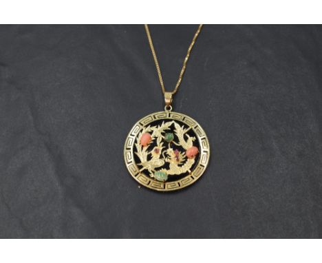 An Oriental Phoenix &amp; Dragon pendant having coral, jade and ruby chip decoration on a black background in 14ct gold mount