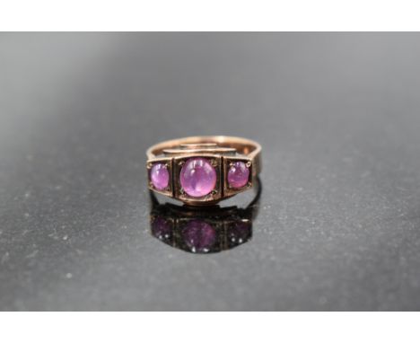 A three stone ruby cabochon ring in a panelled mount on a rose gold loop, no marks, probably gold, size M &amp; approx 3.6g