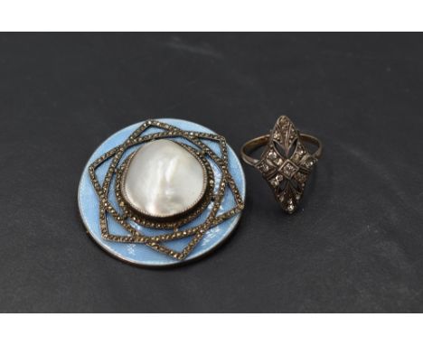 A circular brooch having central mother of pearl panel with star shaped marcasite decoration on a blue enamel guilloche backg