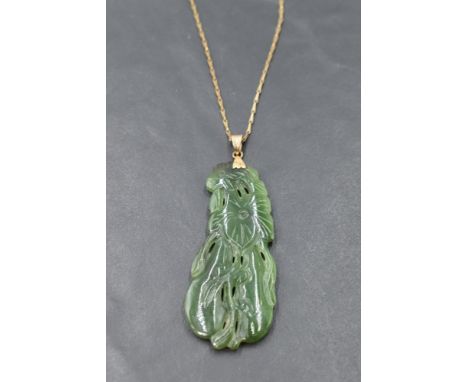 A carved jade pendant with yellow metal loop stamped 14K on an 8ct gold chain, approx 20' &amp; GW 14.2g