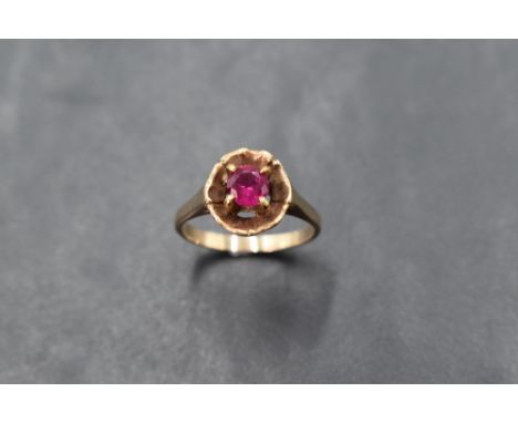 A ruby solitaire ring in a four claw setting in a flower style mount on a gold loop, marks worn, size L &amp; approx 3g