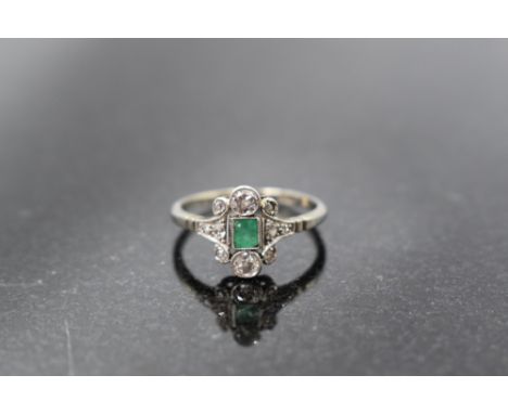 An 18ct white gold and platinum set emerald and diamond ring, the central emerald cut emerald, enclosed by ten small diamonds