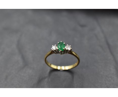 An emerald and diamond trio ring, approx 0.2ct &amp; 0.06ct x 2 in a claw set basket mount on an 18ct gold loop, size O &amp;