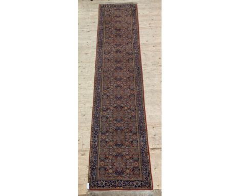 A Persian runner rug, busy red field within a guarded border