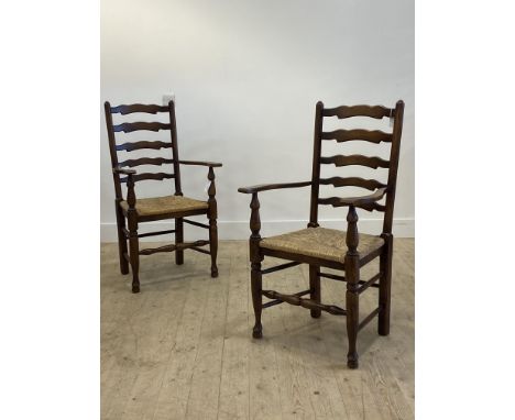 A pair of stained oak ladder back carver dining chairs, 20th century, with string seat, raised on turned supports H106cm