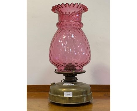 A late Victorian brass oil lamp with moulded cranberry glass shade H48cm