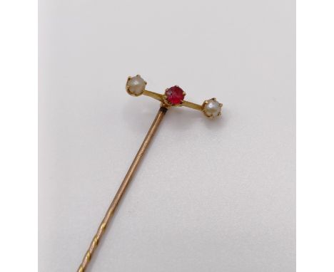 A stick pin, inset with a red coloured stone and seed pearls 