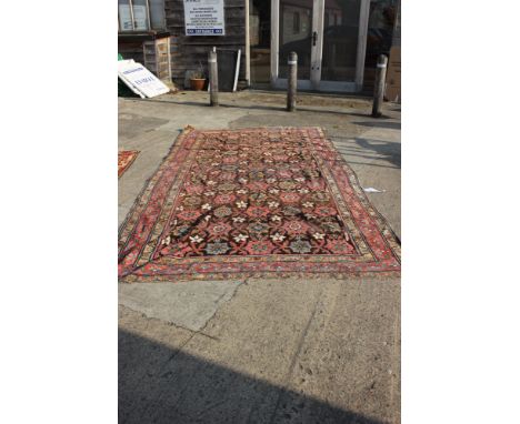 A Hamadan carpet of traditional design with all-over floral design on a dark ground and multi-bordered in shades of red, yell