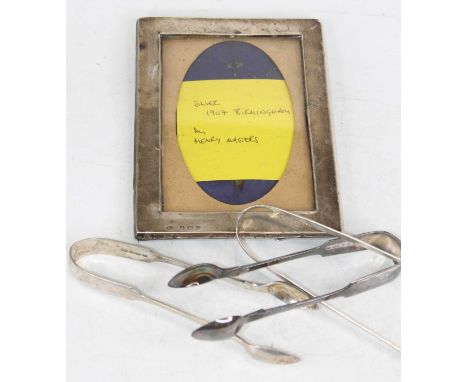 An early 20th century silver clad easel photograph frame, h.16cm; together with a pair of silver sugar tongs; and two plated 
