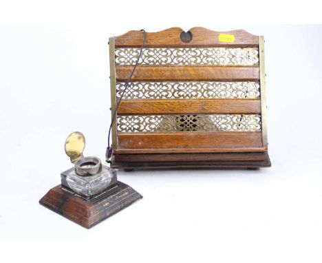 An early 20th century oak and pierced brass bookstand, height 26cm, together with a leather clad inkwell, having a silver lid