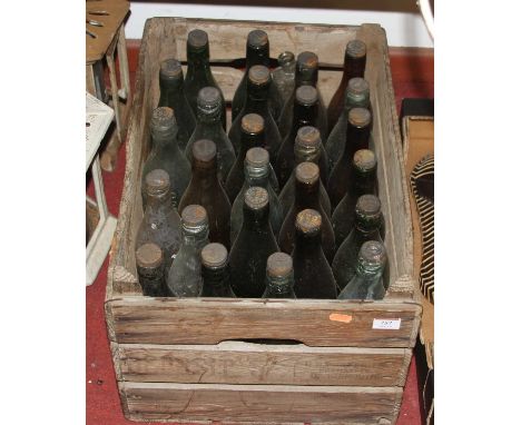 A vintage wooden crate containing glass bottles, mainly local examplesNo paper labels present, but many of them are cast with