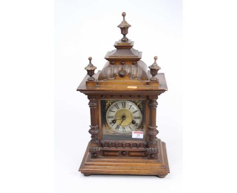 An early 20th century continental walnut cased mantel clock, the silvered chapter ring showing Roman numerals and having pier