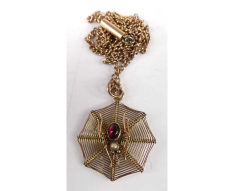 A 9ct gold pendant fashioned as a spider web, the spider set with a cabochon ruby and seed pearl, on a 9ct gold fine curblink