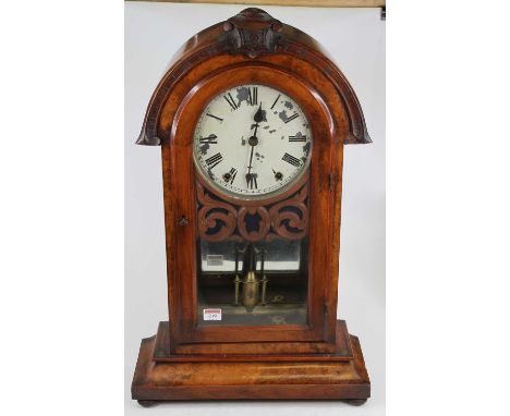 A late Victorian walnut cased dome top mantel clock, having a carved pediment, a painted dial with Roman numerals and twin wi