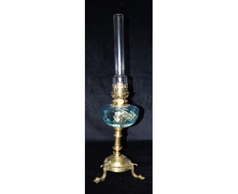 AN EARLY 20TH CENTURY CONTINENTAL OIL LAMP  with blue glass reservoir, the brass base with three dolphon supports, 60cm high 